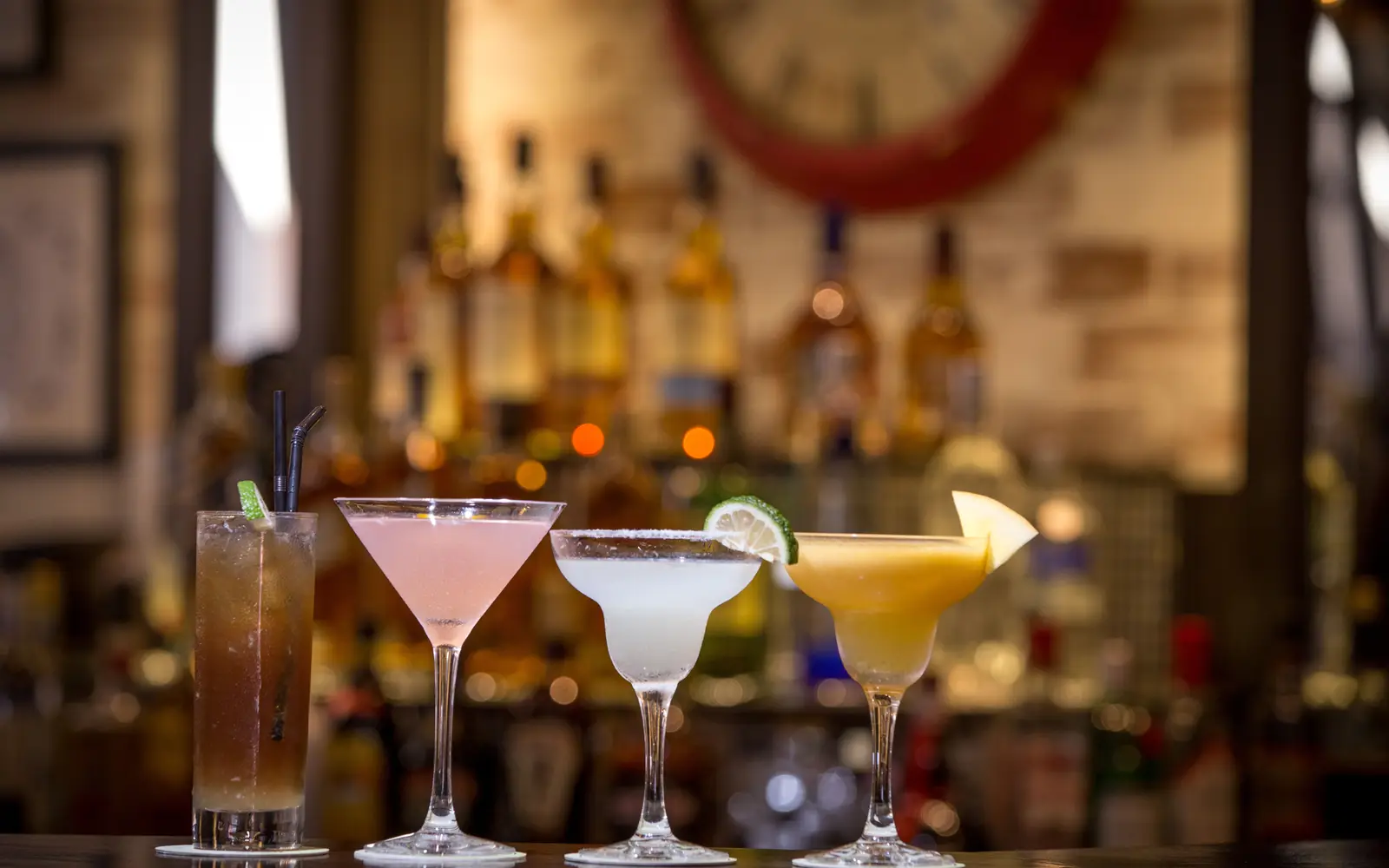 Colorful cocktails with garnishes lined up on a bar counter