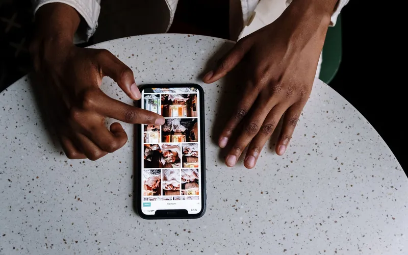 Hands scrolling a smartphone on a round cafe table