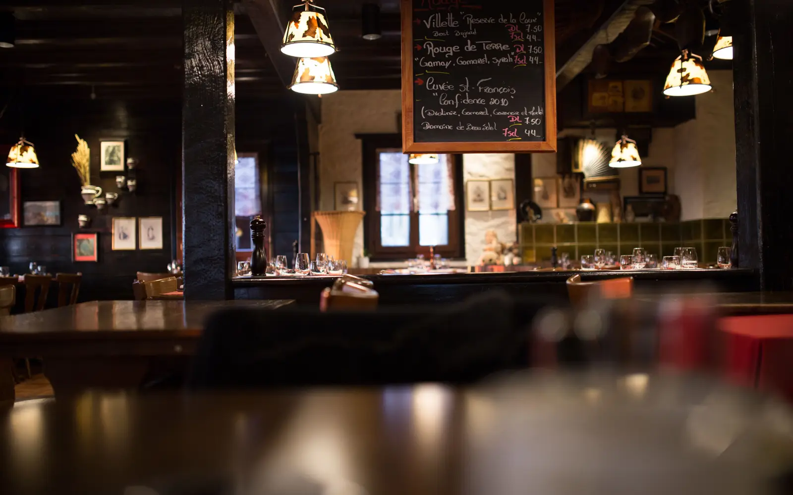 Warm, dimly lit dining room with wooden tables and a vintage bar