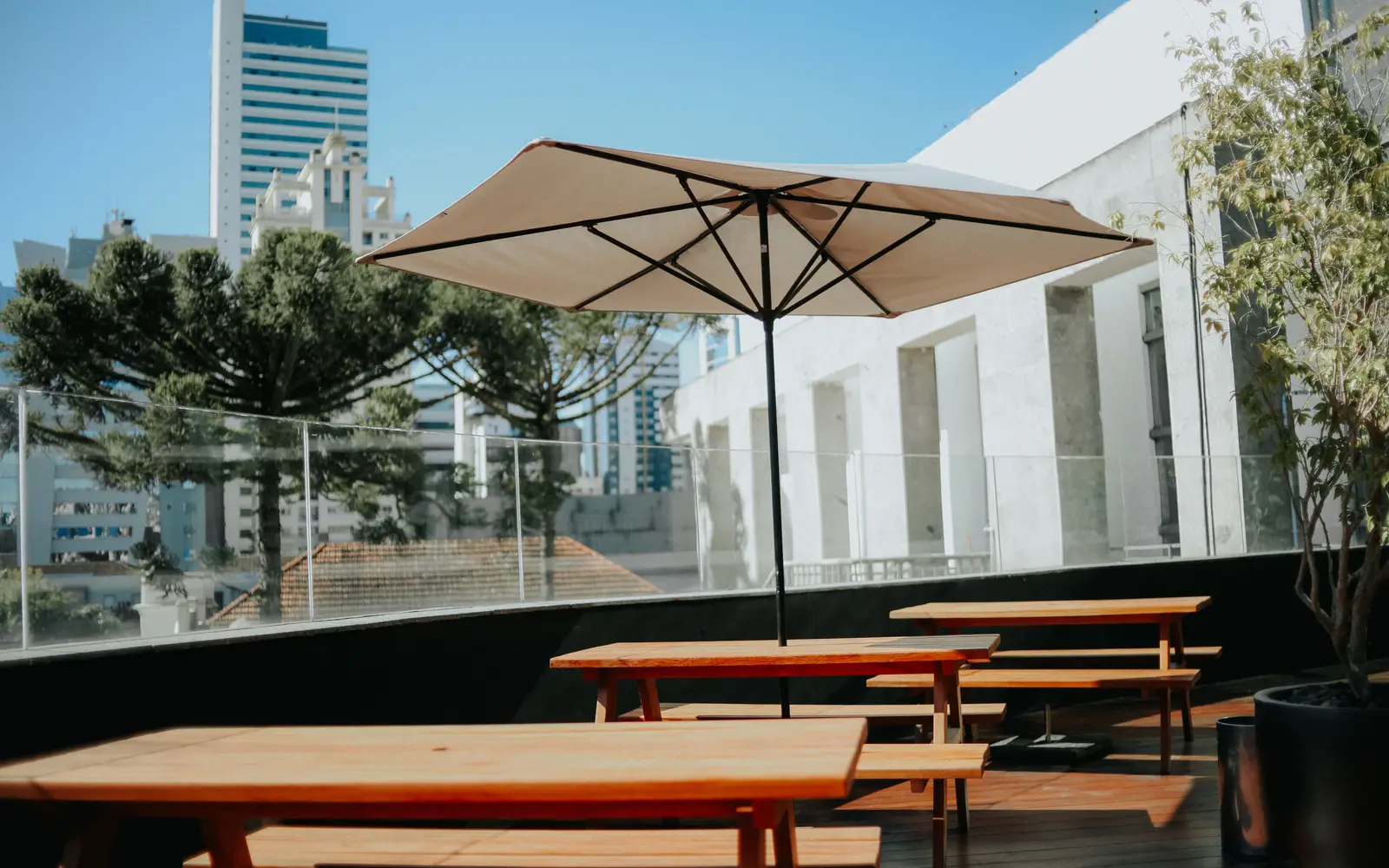 Rooftop patio with wooden seating and a parasol above a city skyline